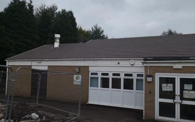 A building with a brown roof and a fence, showcasing its new installation